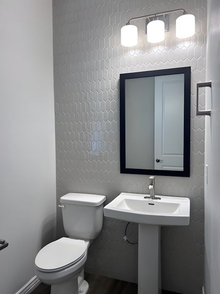 A sleek bathroom featuring hexagonal tiles, a pedestal sink, and contemporary lighting. A sleek bathroom featuring hexagonal tiles, a pedestal sink, and contemporary lighting.