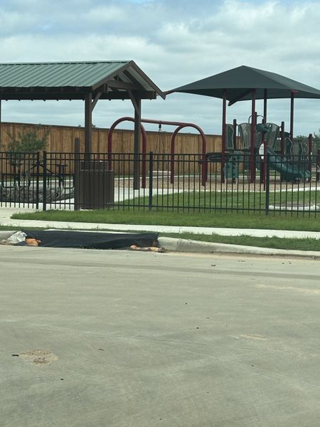 A charming playground with covered structures and a fenced area in Royal Pines by Starlight Homes (Porter, TX).