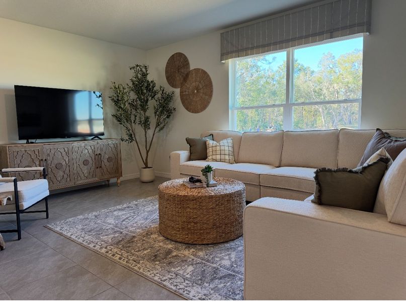 A cozy living room with a large sectional sofa, stylish TV console, and elegant decor accentuated by natural light.