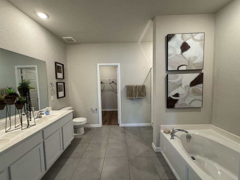 Modern bathroom featuring a double vanity, large mirror, soaking tub, and abstract artwork for a touch of elegance.