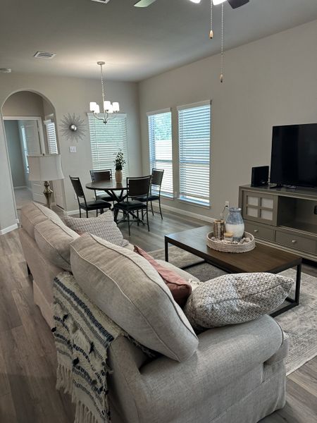 An inviting living room with a cozy beige sofa, elegant dining area, and large windows for natural light. An inviting living room with a cozy beige sofa, elegant dining area, and large windows for natural light.