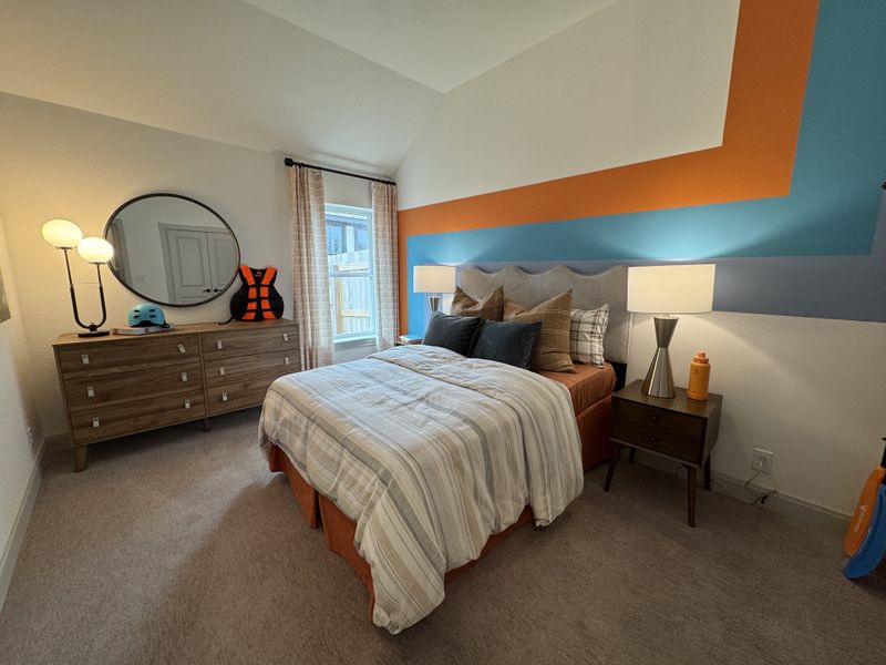 A cozy bedroom with a chic geometric accent wall, stylish lamps, and a wooden dresser with modern decor.