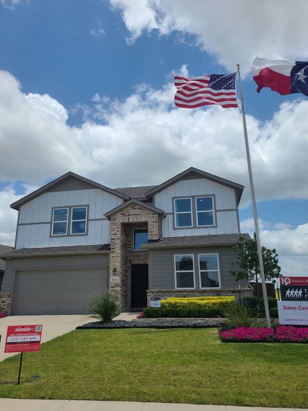 A charming two-story home with a brick and siding exterior in River Ridge by Taylor Morrison (Crandall, TX). Lush landscaping adorns the yard.