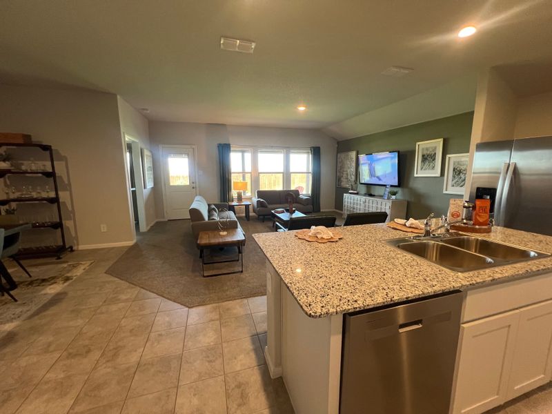 An open-concept living area with a granite kitchen island, comfortable seating, large windows, and modern decor. An open-concept living area with a granite kitchen island, comfortable seating, large windows, and modern decor.