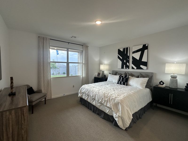 A serene primary bedroom with neutral tones, large windows, and stylish black-and-white artwork for a modern touch.