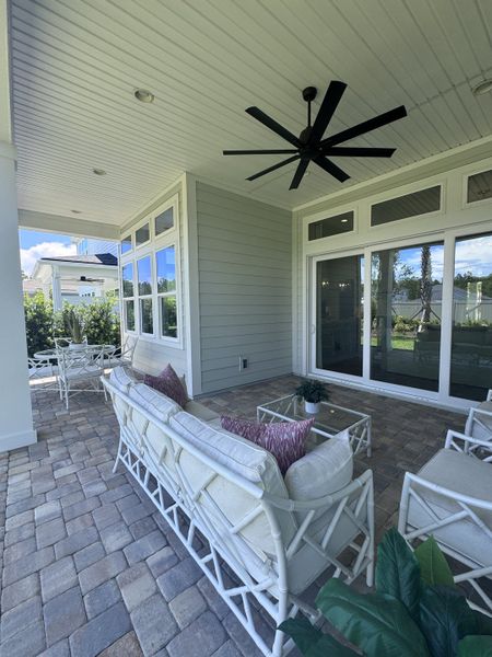 A cozy patio with wicker seating, plush cushions, and ceiling fan, perfect for relaxing. 