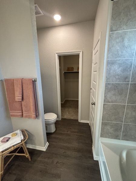 A cozy bathroom featuring wood flooring, soft lighting, and a spacious walk-in closet access for modern convenience.