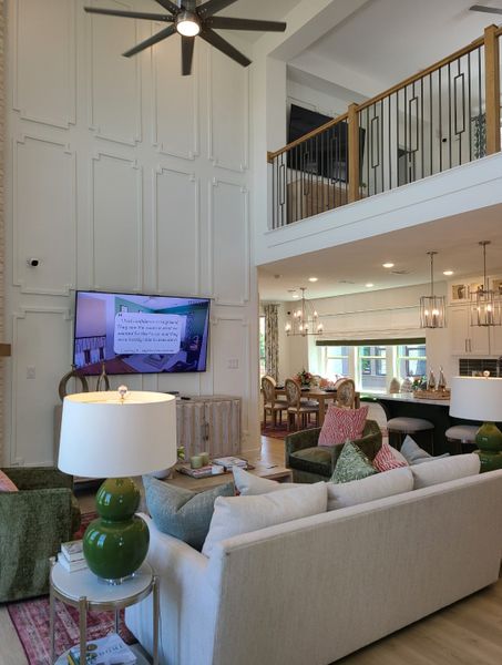 A spacious living area with high ceilings, elegant panel walls, and stylish decor, featuring a cozy seating arrangement and modern lighting.