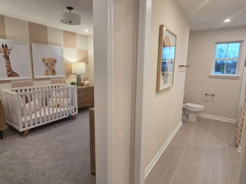 A cozy nursery with animal art, a white crib, and an adjoining neutral-toned bathroom with modern fixtures.