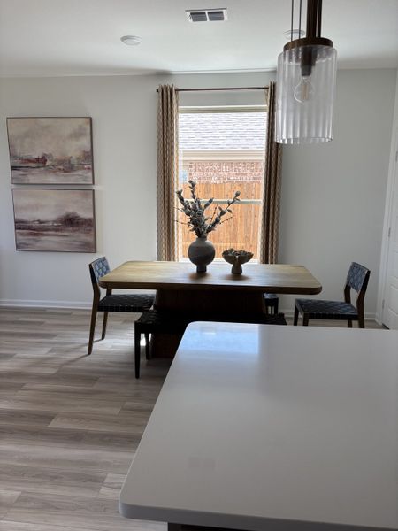 A cozy dining area with a wooden table, modern chairs, elegant decor, and soft natural lighting.