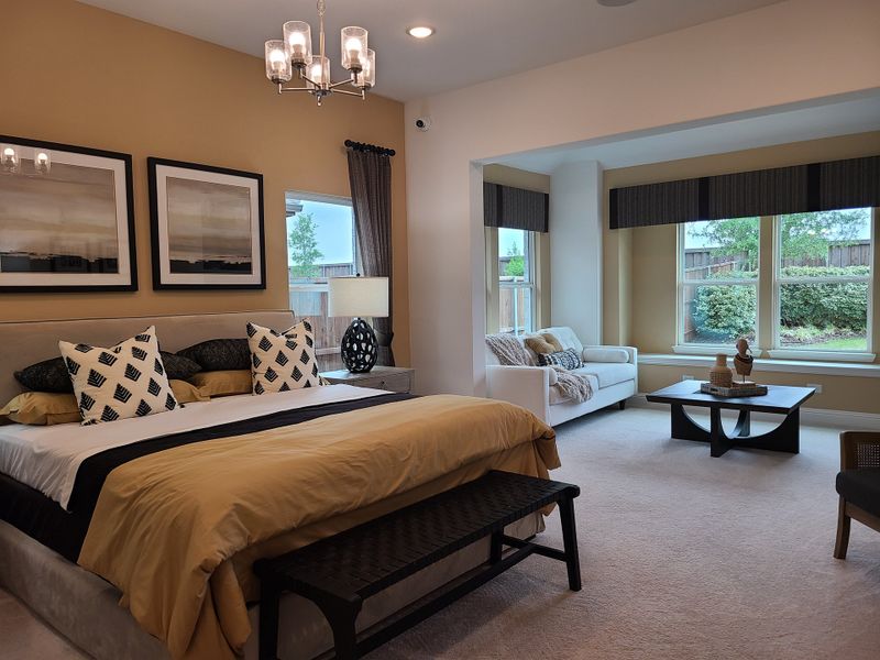 A spacious bedroom with elegant decor, featuring a cozy seating area and large windows overlooking a lush garden. A spacious bedroom with elegant decor, featuring a cozy seating area and large windows overlooking a lush garden.