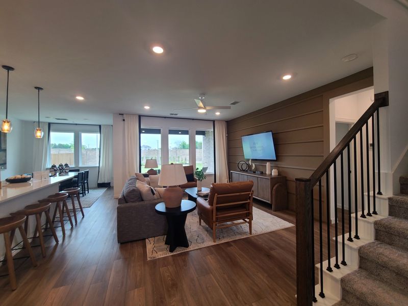 A modern living area featuring hardwood floors, cozy seating, and a sleek kitchen with pendant lighting.