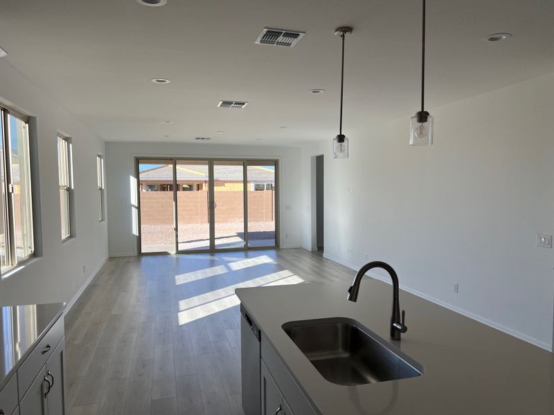 A bright open-concept kitchen and living area with sleek flooring, modern fixtures, and large sliding glass doors.