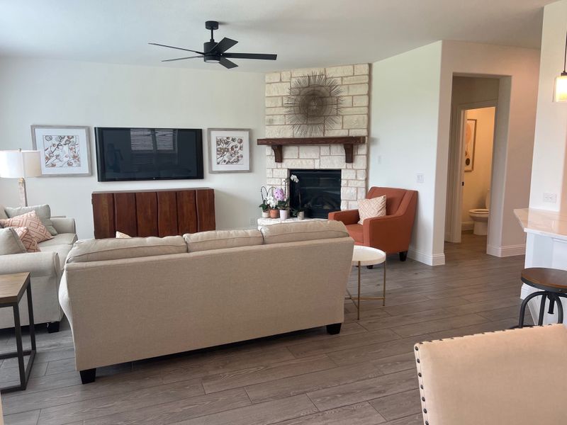 A cozy living room with a stone fireplace, neutral sofas, and a mounted TV, featuring modern decor and wood-like flooring. A cozy living room with a stone fireplace, neutral sofas, and a mounted TV, featuring modern decor and wood-like flooring.