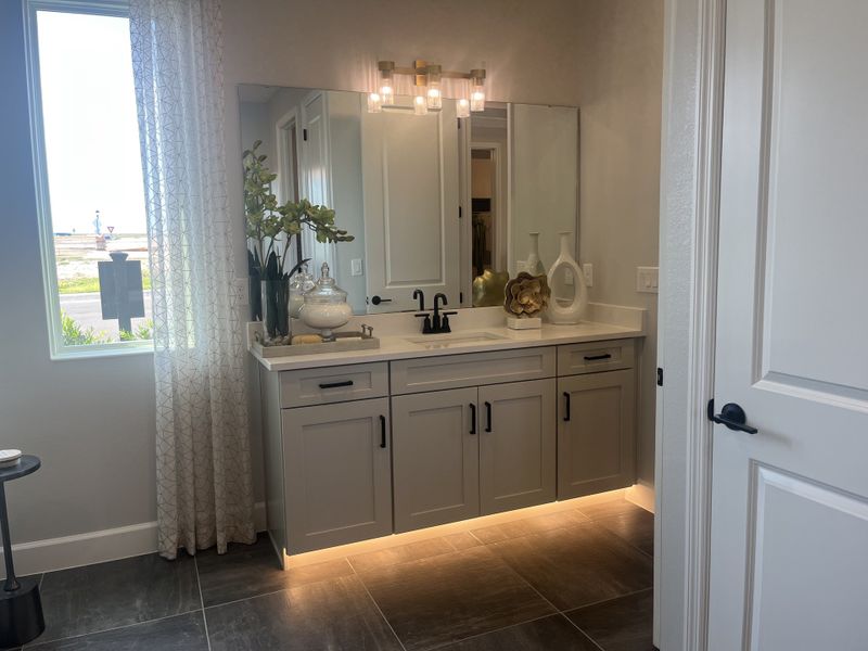 A modern bathroom with sleek gray cabinetry, elegant decor, under-cabinet lighting, and a spacious vanity mirror. A modern bathroom with sleek gray cabinetry, elegant decor, under-cabinet lighting, and a spacious vanity mirror.