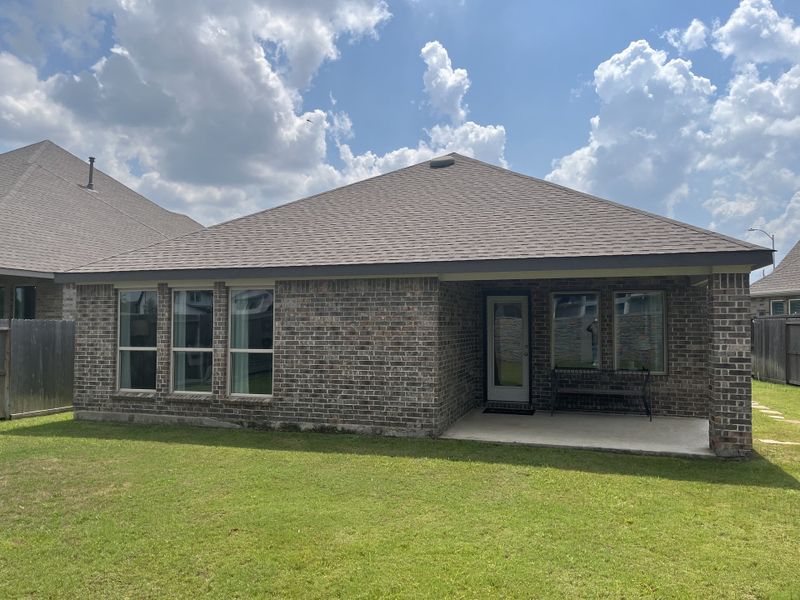 A charming brick home with a cozy patio and lush lawn in Jordan Ranch: Pinnacle Collection by Lennar (Fulshear, TX).