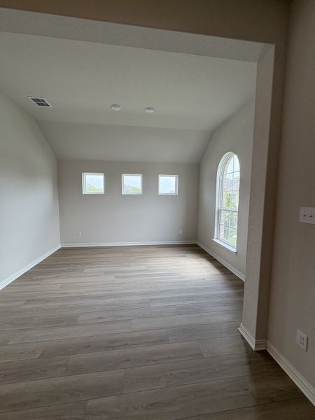 Bright room with light wood floors, arched window, and soft neutral walls offering a serene atmosphere.