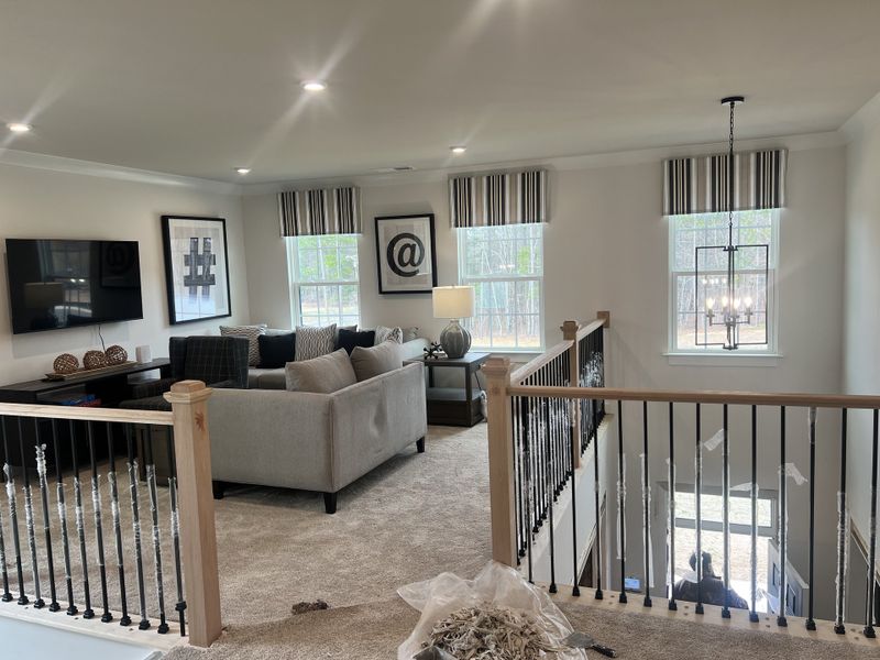 A cozy living area with modern decor, plush carpeting, and striped window treatments, featuring stylish artwork and chic lighting.