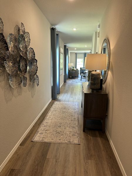 A welcoming hallway with elegant artwork, warm wood flooring, and stylish decor leading into a bright living area.