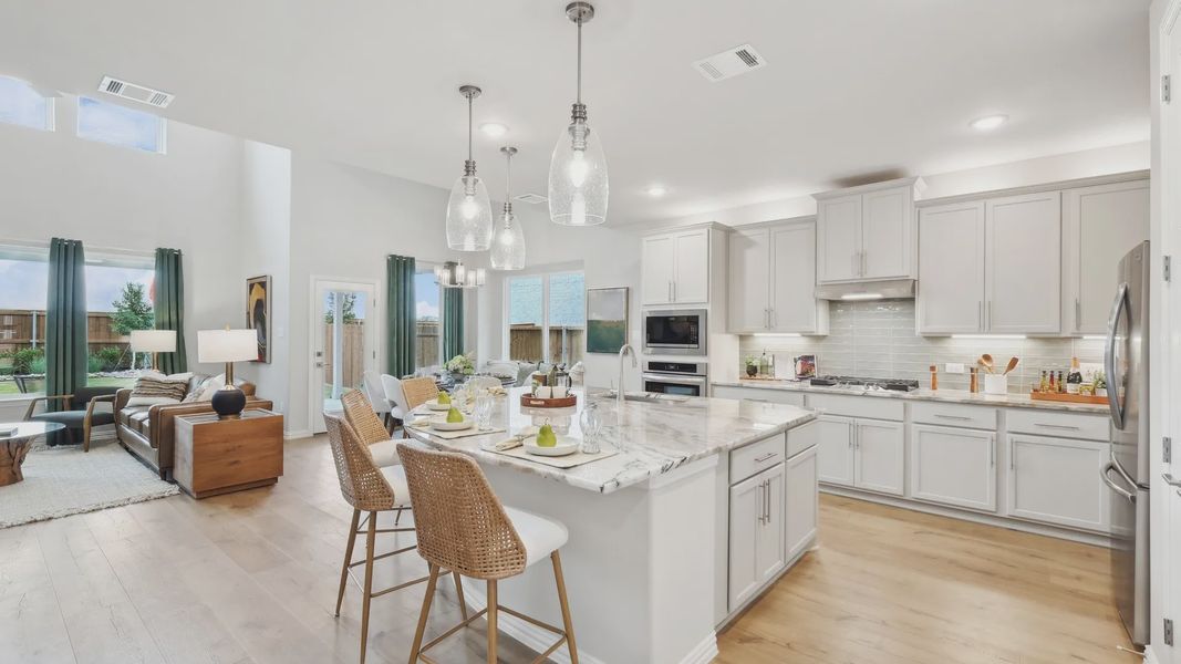 Luxurious marble island and sleek light fixtures elevate this Wildflower Ranch kitchen's elegance. Luxurious marble island and sleek light fixtures elevate this Wildflower Ranch kitchen's elegance.