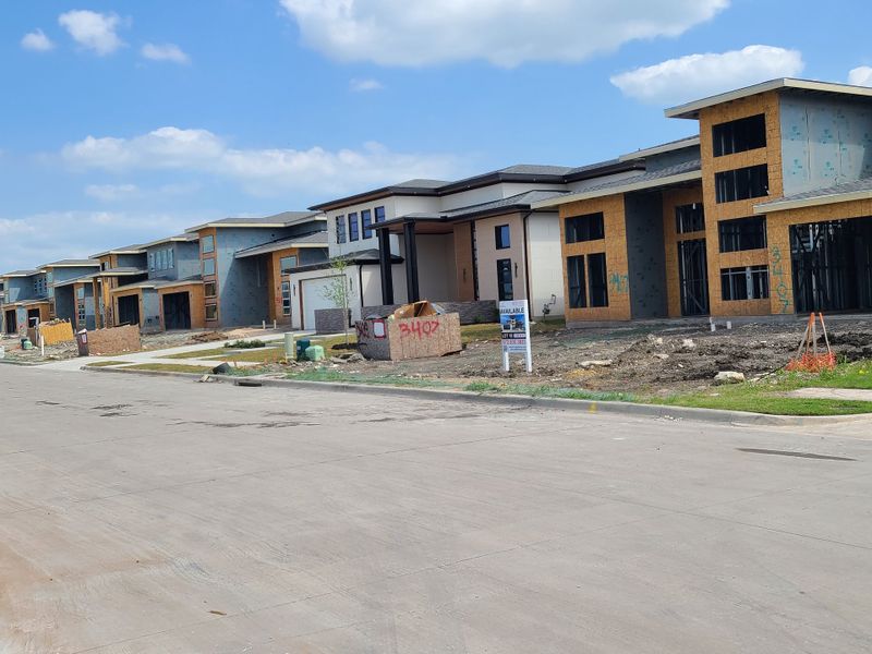 New modern homes under construction on a sunny street in The Dawn by NETZE.HOMES (Melissa, TX).
