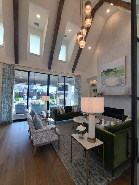 A spacious living room with vaulted ceilings, exposed beams, elegant lighting, and cozy seating opening to a lush outdoor view. A spacious living room with vaulted ceilings, exposed beams, elegant lighting, and cozy seating opening to a lush outdoor view.
