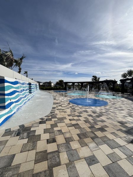 A vibrant outdoor space with fountains and tiled flooring in Central Park Townhomes by D.R. Horton (Port St. Lucie, FL).