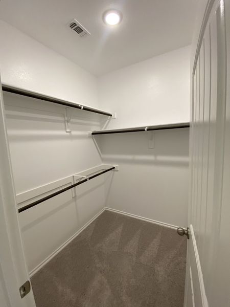 A spacious walk-in closet with ample shelving and soft carpet, offering efficient storage solutions.