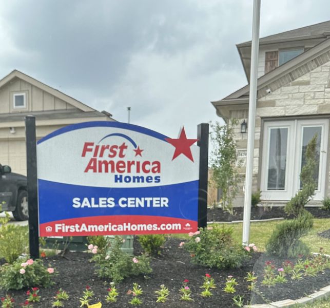 A welcoming sales center for First America Homes in Meadow Park, Conroe, TX, with well-kept gardens and inviting architecture.