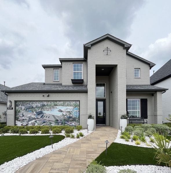 A modern gray brick home with a tidy yard in Venetian by Megatel Homes (Celina, TX).