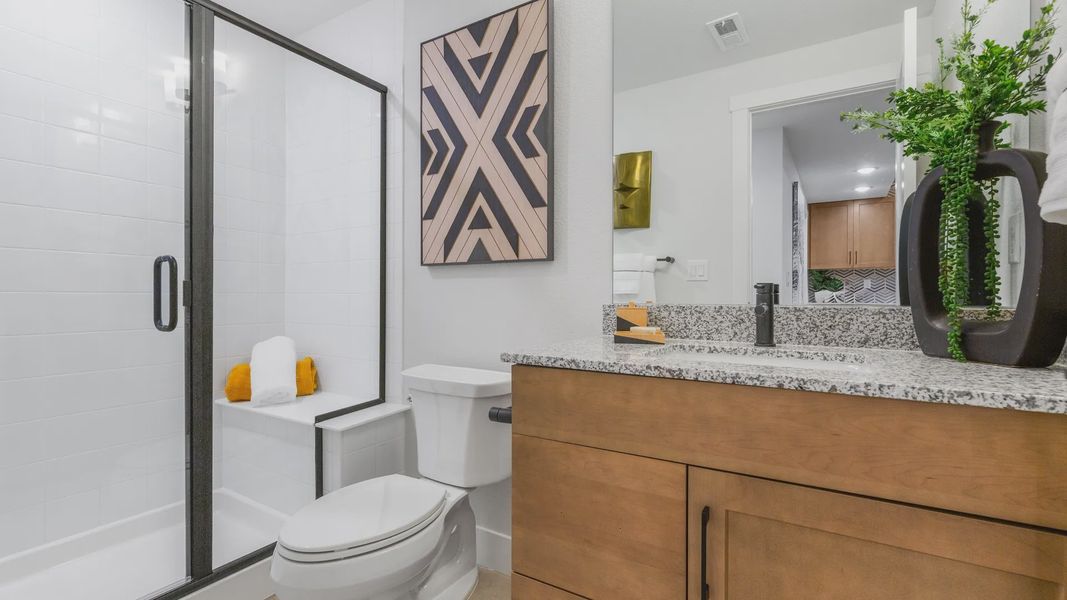 Sleek Dillon Pointe bathroom features granite countertops, elegant wood cabinetry, and pristine glass shower. Sleek Dillon Pointe bathroom features granite countertops, elegant wood cabinetry, and pristine glass shower.