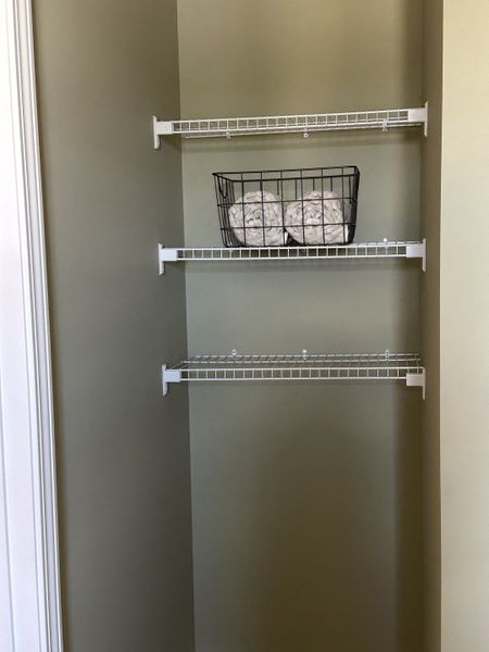 A neat closet with wire shelving and a basket of rolled towels, perfect for organized storage.