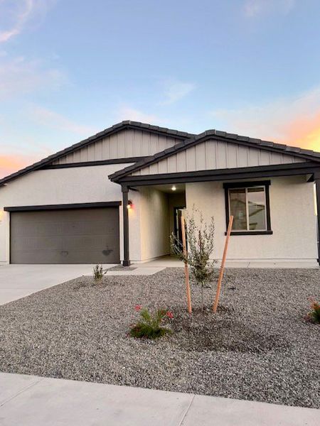 A modern white home with sleek lines, gravel landscaping, and a two-car garage in Agave Trails by Ashton Woods (Buckeye, AZ).