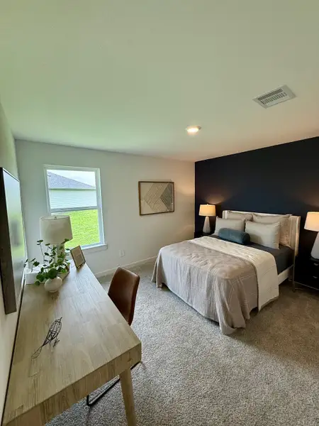 A cozy bedroom with a minimalist design featuring a dark accent wall, a stylish desk, and warm ambient lighting.