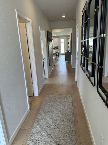 A sleek hallway with wood flooring, neutral walls, and modern decor, leading to a bright living area. A sleek hallway with wood flooring, neutral walls, and modern decor, leading to a bright living area.