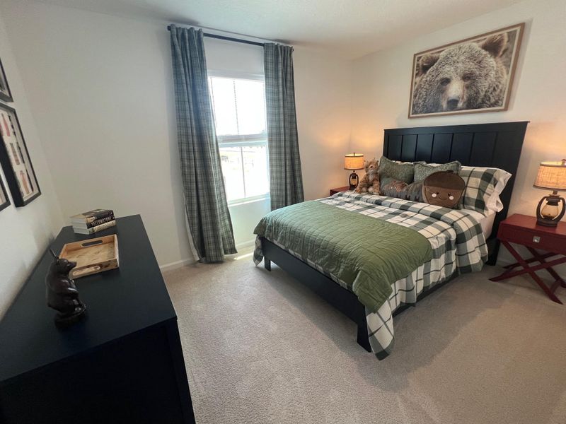 A cozy bedroom featuring a plaid bedspread, playful bear decor, and soft lighting for a welcoming atmosphere.