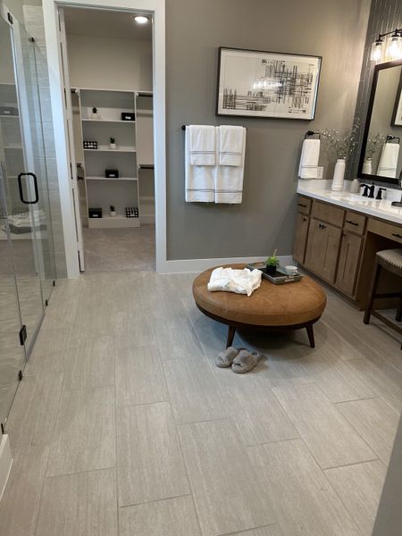 A modern bathroom with sleek tile flooring, warm wood vanity, and chic decor leading to a stylish walk-in closet.
