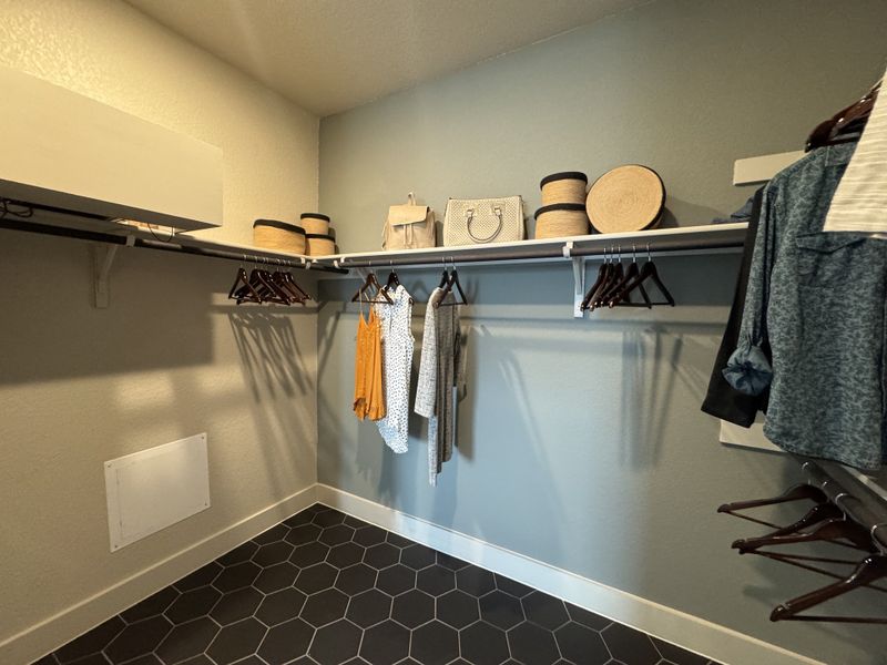A spacious walk-in closet with hexagonal floor tiles, ample shelving, and hanging space for a well-organized wardrobe.