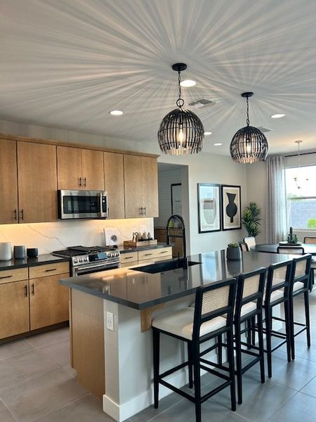 A modern kitchen with a sleek island, chic pendant lights, and light wood cabinetry.