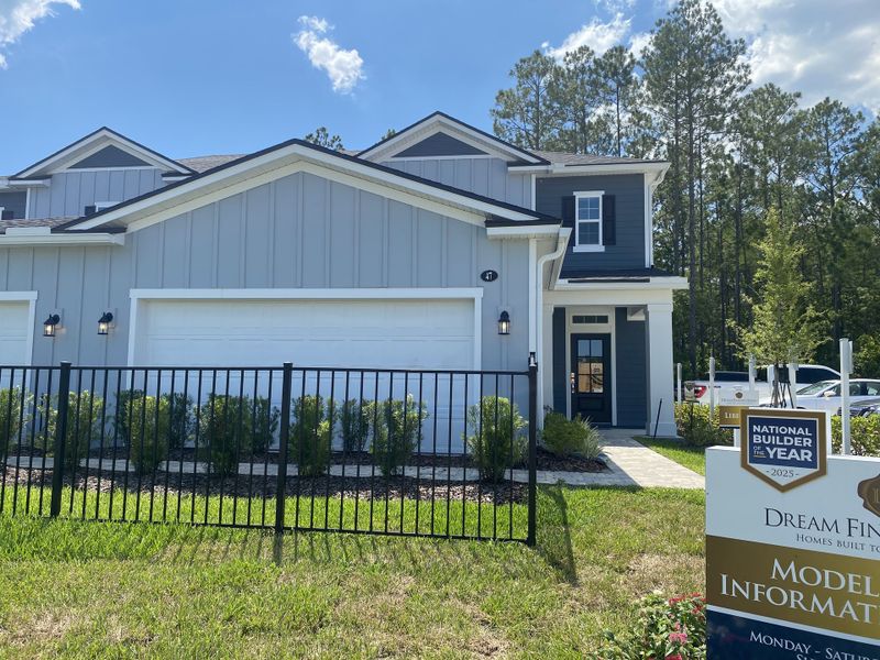 A charming blue and white home with a manicured lawn in Holly Landing at SilverLeaf by Dream Finders Homes (St. Augustine, FL).
