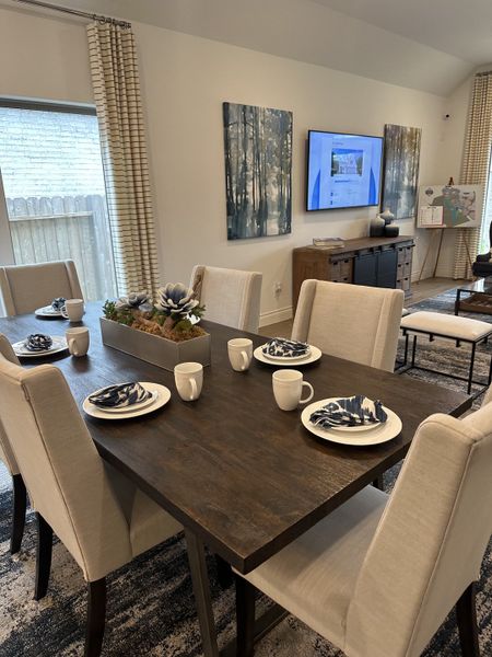A modern dining room with a dark wooden table, upholstered chairs, and abstract art, creating a cozy yet refined atmosphere.