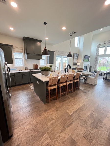 A modern kitchen with dark cabinetry, a spacious island, and elegant pendant lighting over wooden flooring. A modern kitchen with dark cabinetry, a spacious island, and elegant pendant lighting over wooden flooring.
