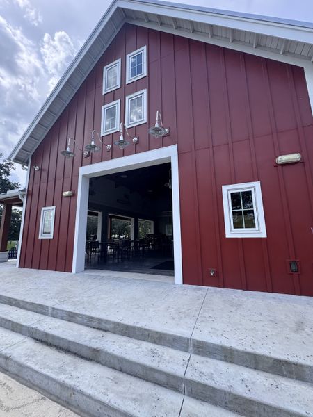A charming red barn with white trim and outdoor lighting in Granary Park: Granary Park 40s by Lennar (Green Cove Springs, FL).