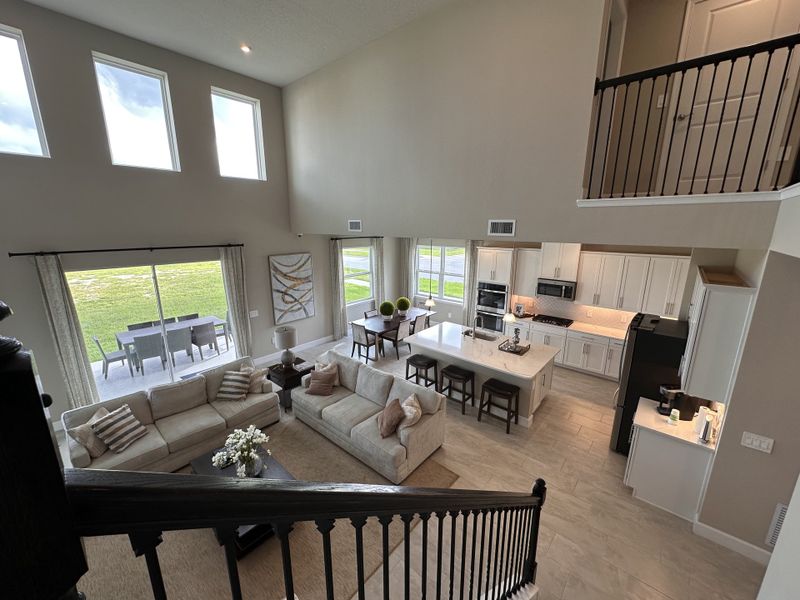 A spacious open-concept living area with high ceilings, plush seating, and a modern kitchen with an island and dining space.
