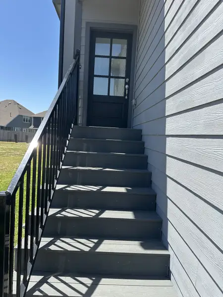 A modern gray exterior staircase leading to a stylish entry door in Woodforest by Chesmar Homes (Montgomery, TX). A modern gray exterior staircase leading to a stylish entry door in Woodforest by Chesmar Homes (Montgomery, TX).