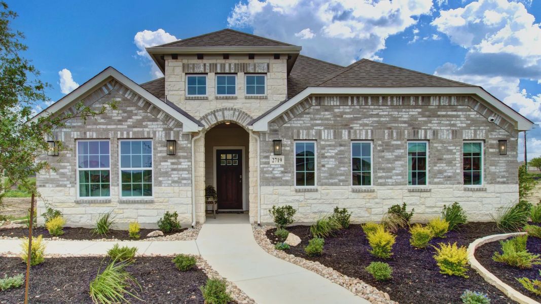 Elegant brick facade with arched entrance and pristine landscaping in Prairie Green community.