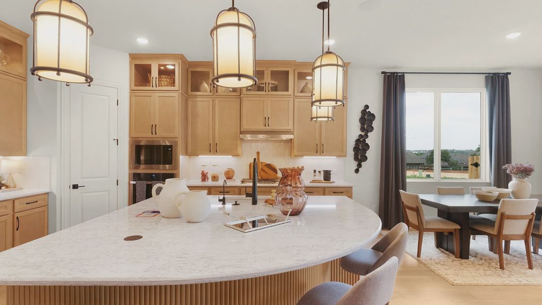 Modern kitchen with ceiling-height cabinets, built-in appliances, statement lighting, and a large center island.