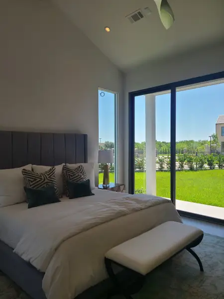 A bright and modern bedroom with floor-to-ceiling windows, a cozy bed, and green views outside.