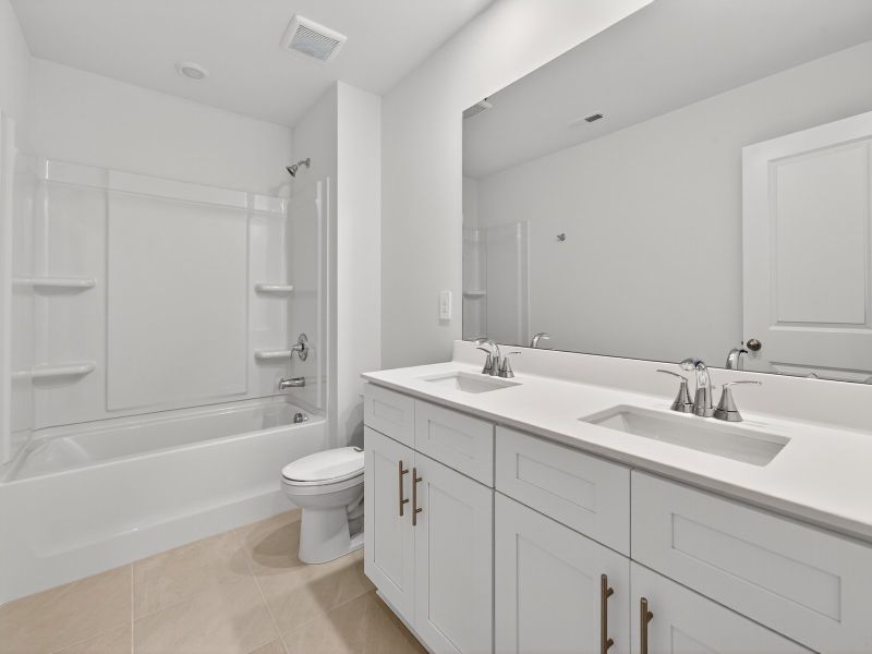 The secondary bathroom features a dual-sink vanity and oversized shower tub.