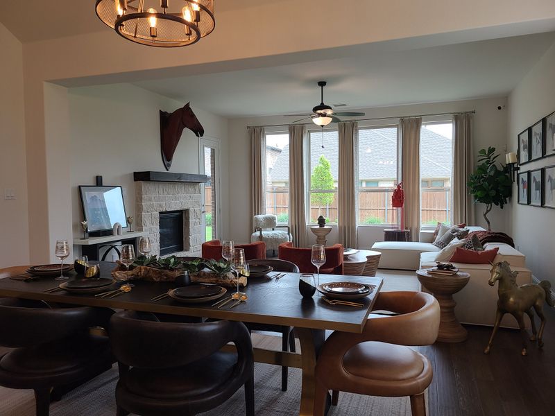 A modern living and dining area featuring a cozy fireplace, stylish decor, and abundant natural light from large windows.